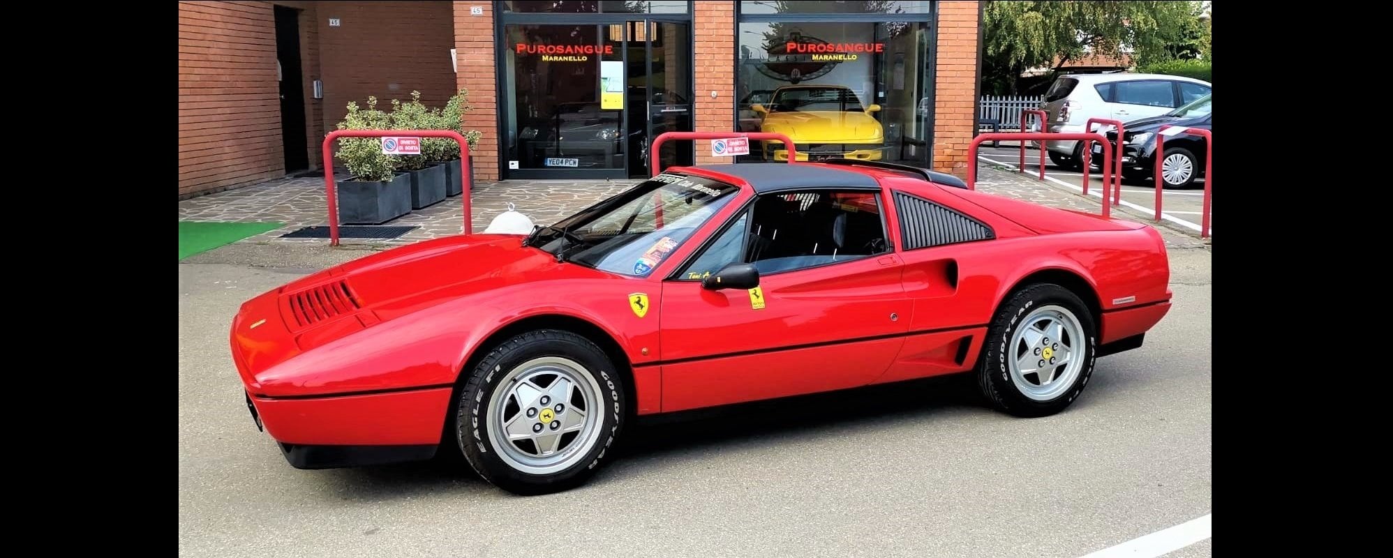 Purosangue Maranello showcase with a Ferrari 308 in front 