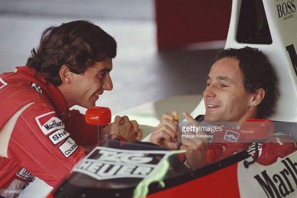 Ayrton Senna, driver of the McLaren-Honda MP4/5B, shares a funny joke with team mate Gerhard Berger (in car) during pre-season testing on 1st February 1990 at the Autodromo Enzo e Dino Ferrari in Imola, San Marino. Photo by Pascal Rondeau / Getty Images.