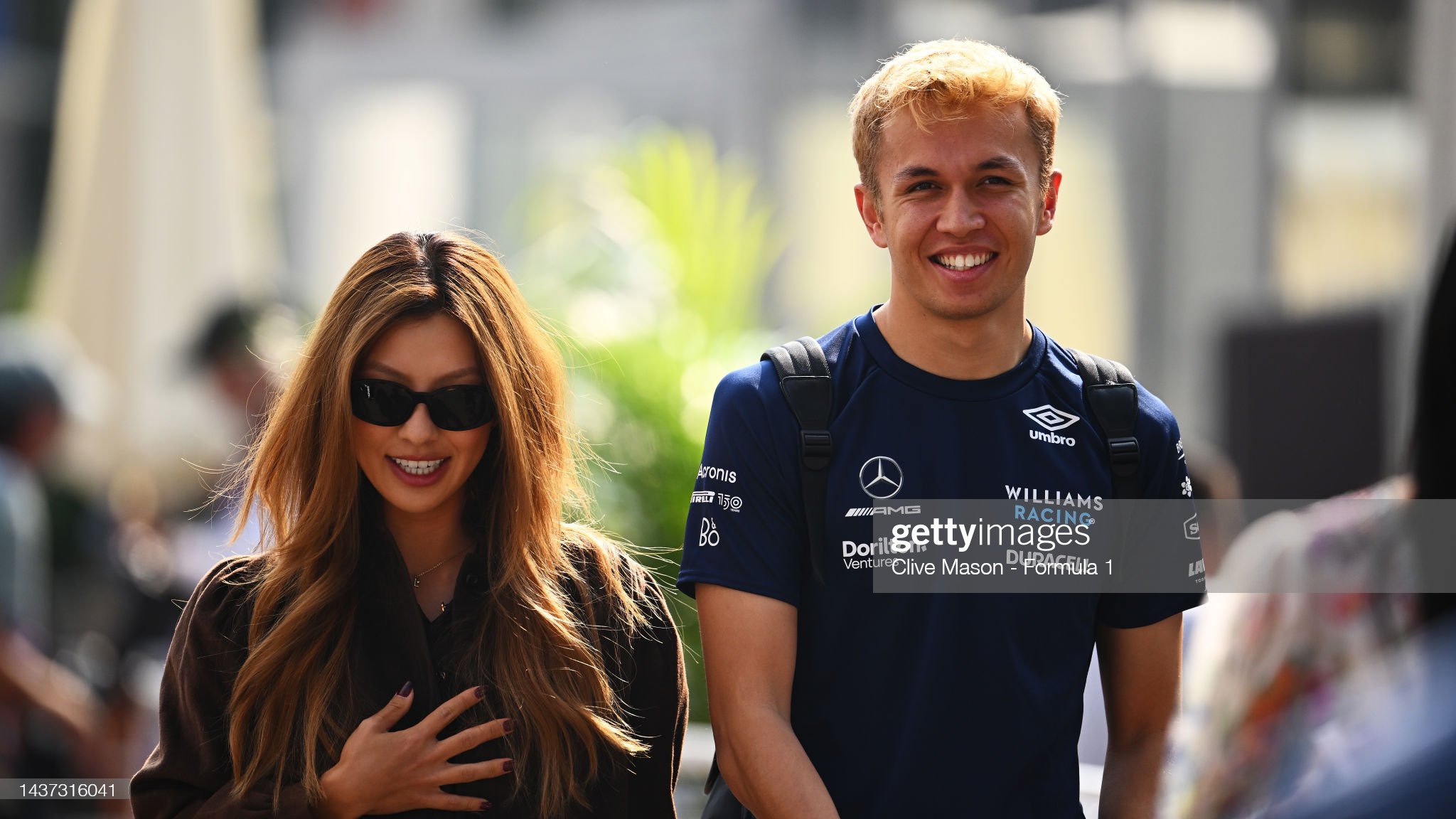 Alexander Albon of Thailand and Williams and Lily Muni He walk in the paddock.