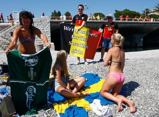 Belgian fans show their flag with “we’re just here for the Swedish girls” written on to Swedish fans on the beach in Nice.
