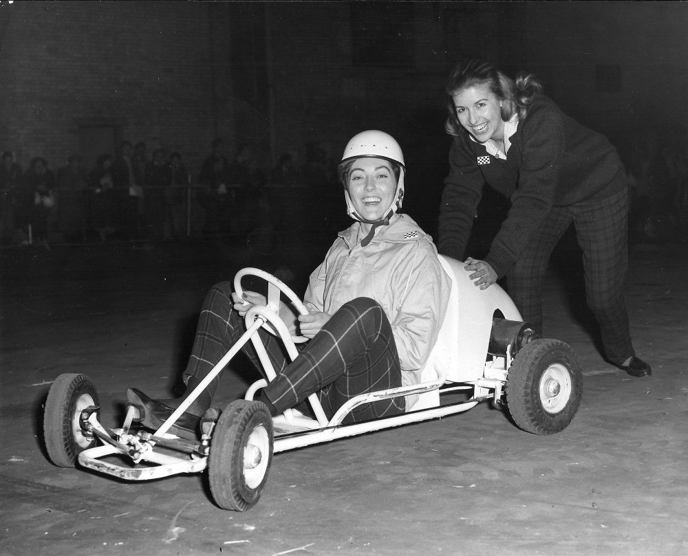 A woman in a kart pushed by another woman.