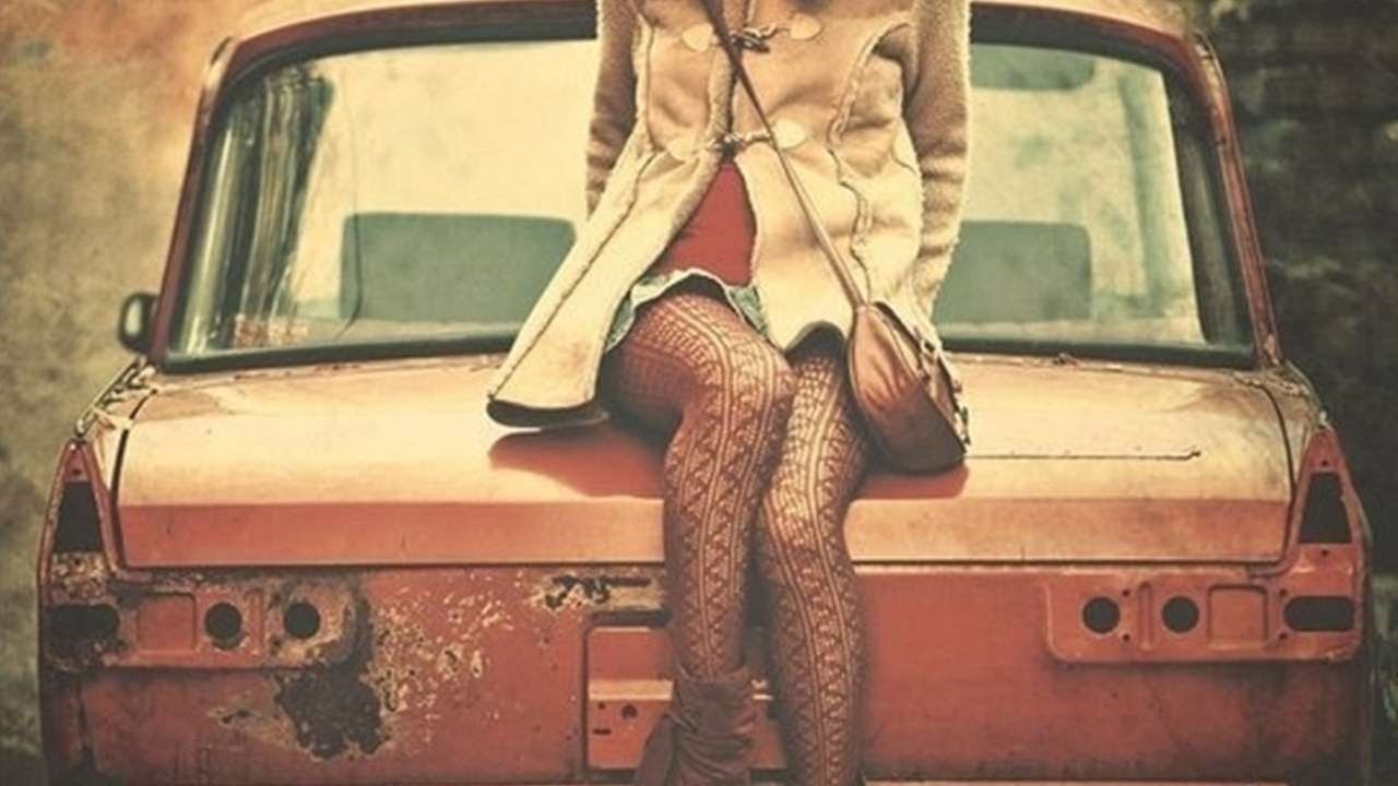 A girl on a rusted Moskvitch.