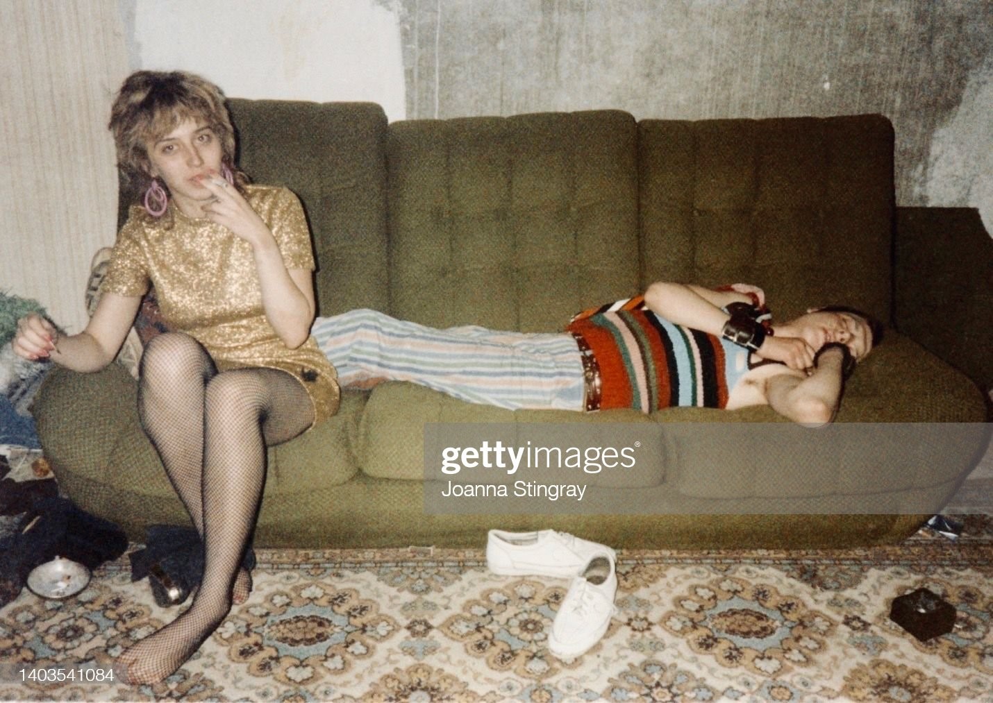 An unidentified woman sits on a sofa beside sleeping Russian Punk musician 'Pig' Panov, Leningrad, Russia, 1986. 