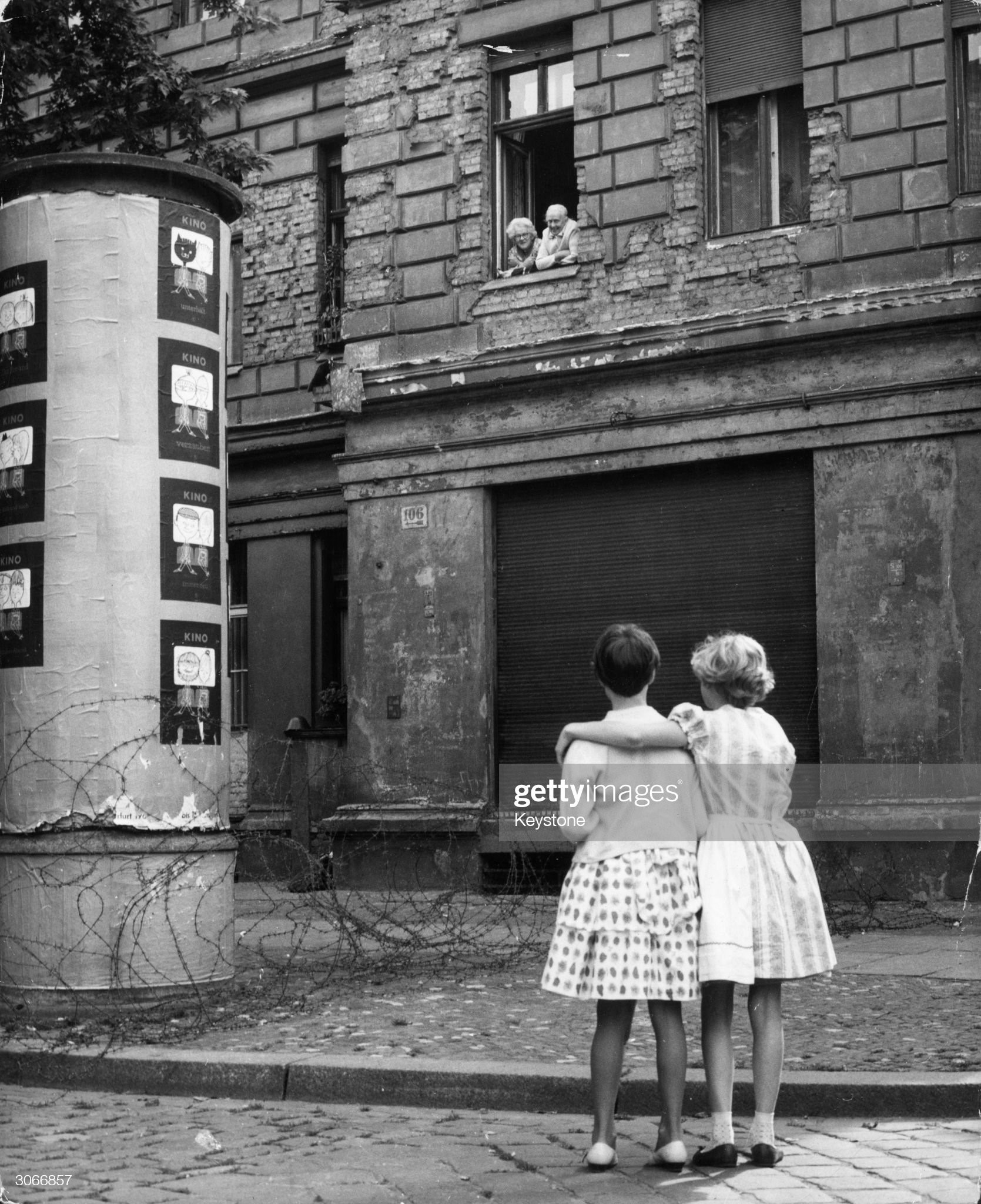 14th August 1961: two little girls in a West German street chat with their grandparents in the window of their home in the eastern zone, separated only by a barbed wire barricade.