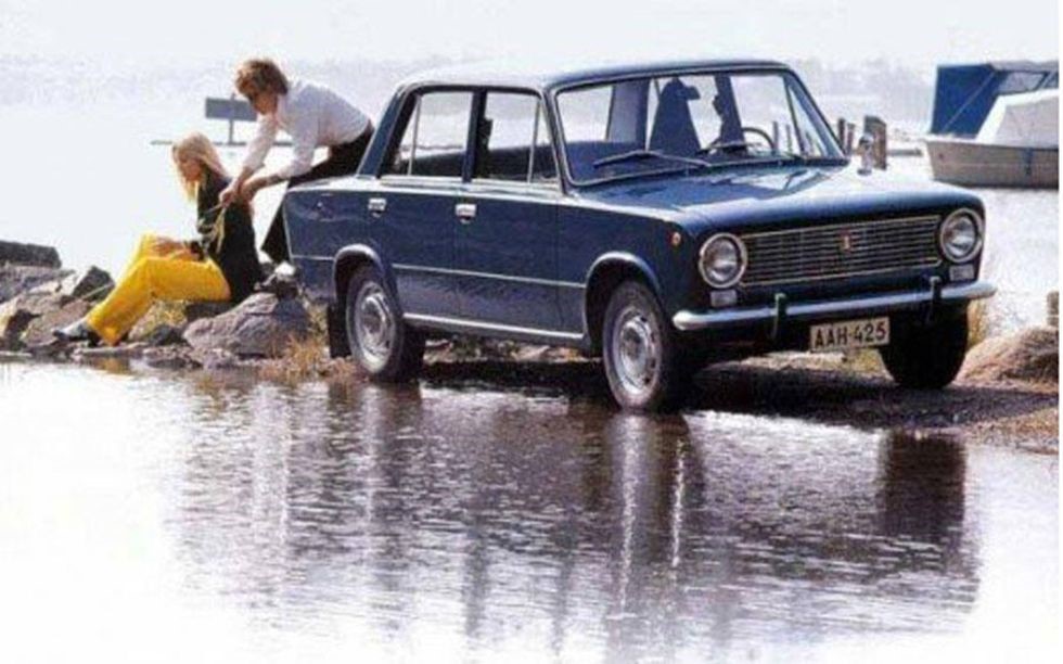 A couple and their Lada relax by the water.