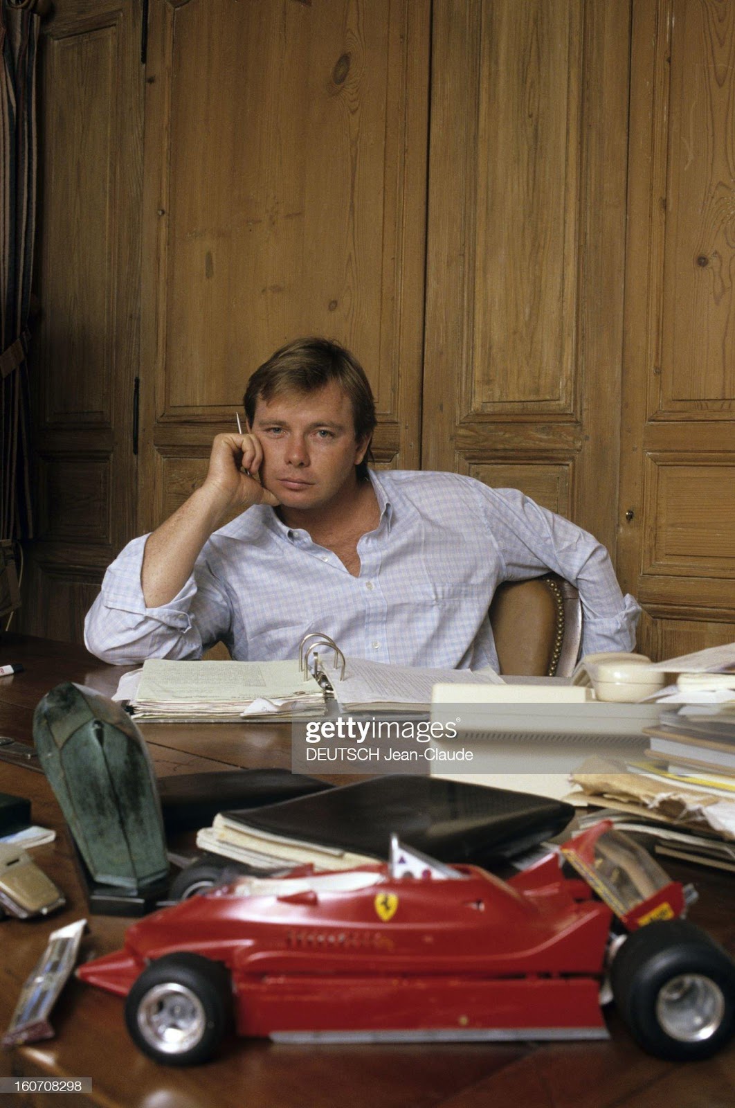 Didier Pironi at home, sitting at his desk, a miniature Ferrari car in the foreground.