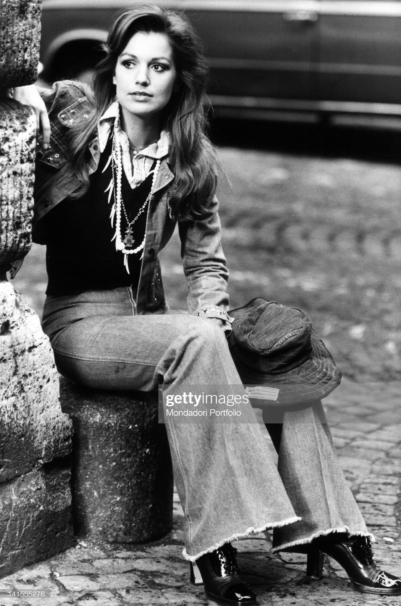 Catherine Spaak sitting in a corner of a street in Rome in 1970s. 