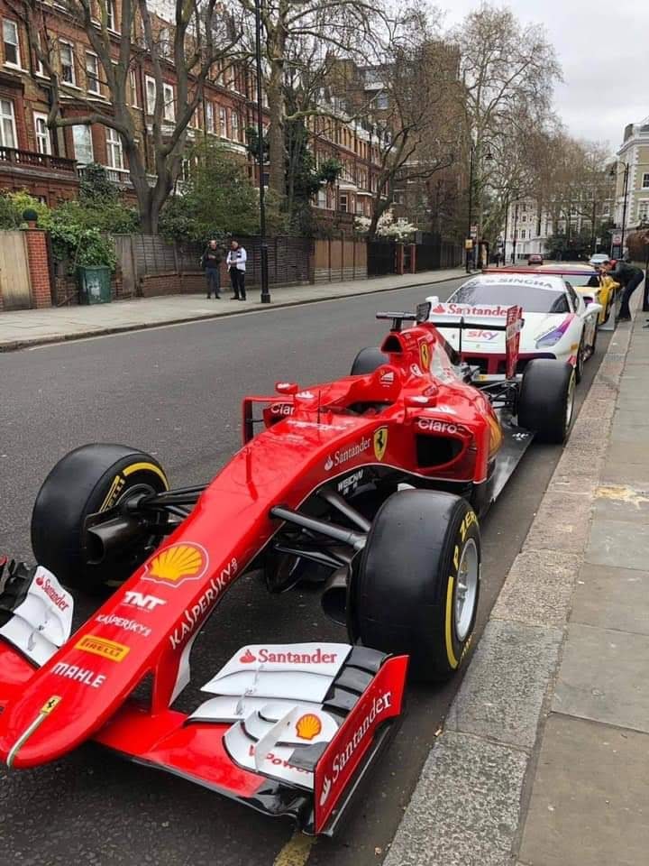 A Ferrari F1 parked in a city.
