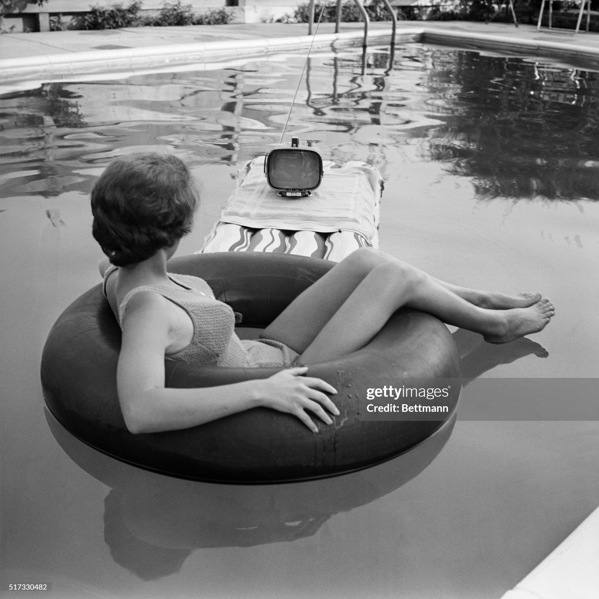 August 01, 1962. Nineteen year old Joyce McGee relaxes in front of the television while cooling off in the swimming pool. 
