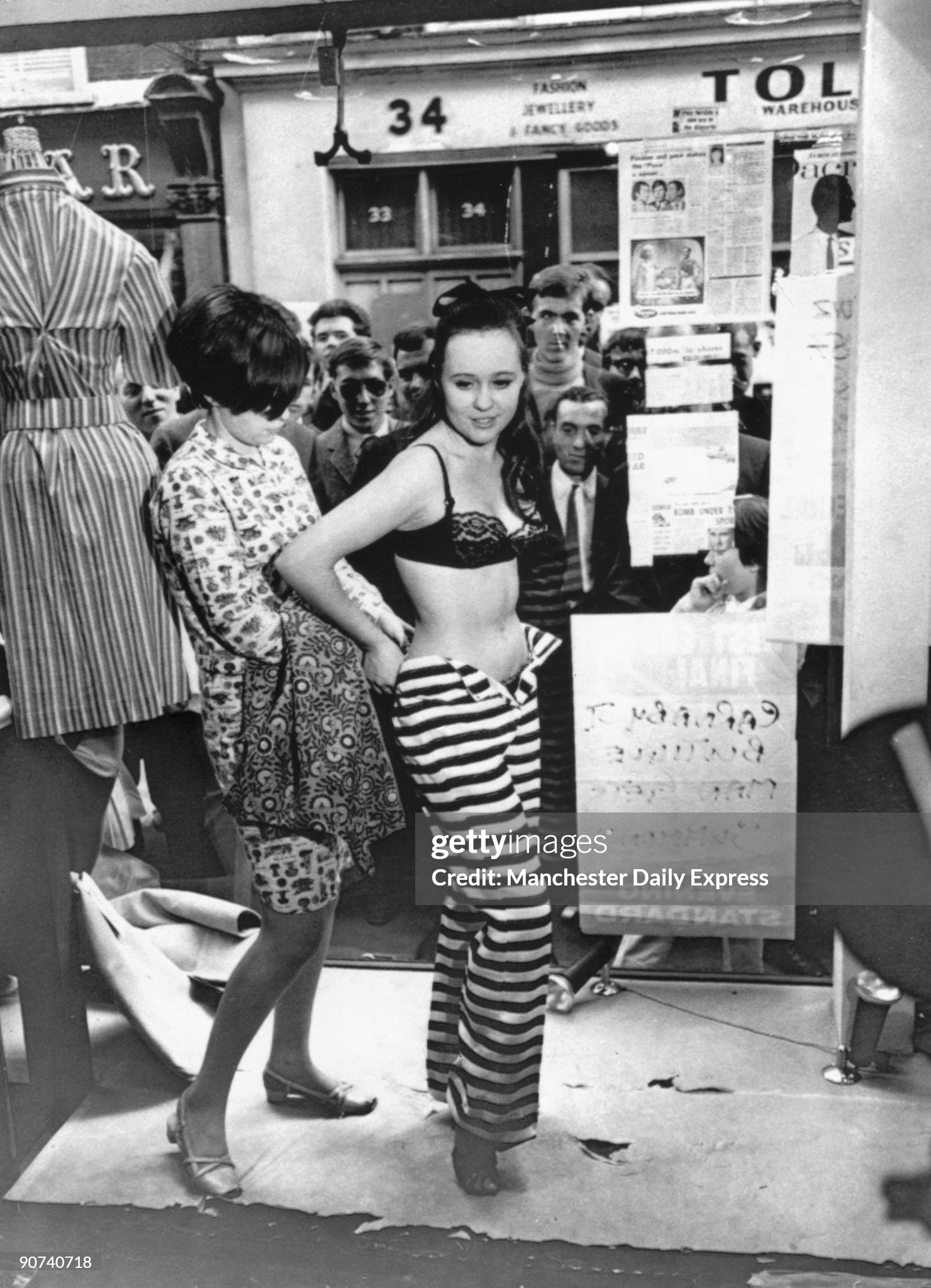 13 May 1966. Crowds of men look through the window of the ‘Lady Jane’ clothes boutique on Carnaby Street, London, whilst a model is dressed in the latest fashions. 