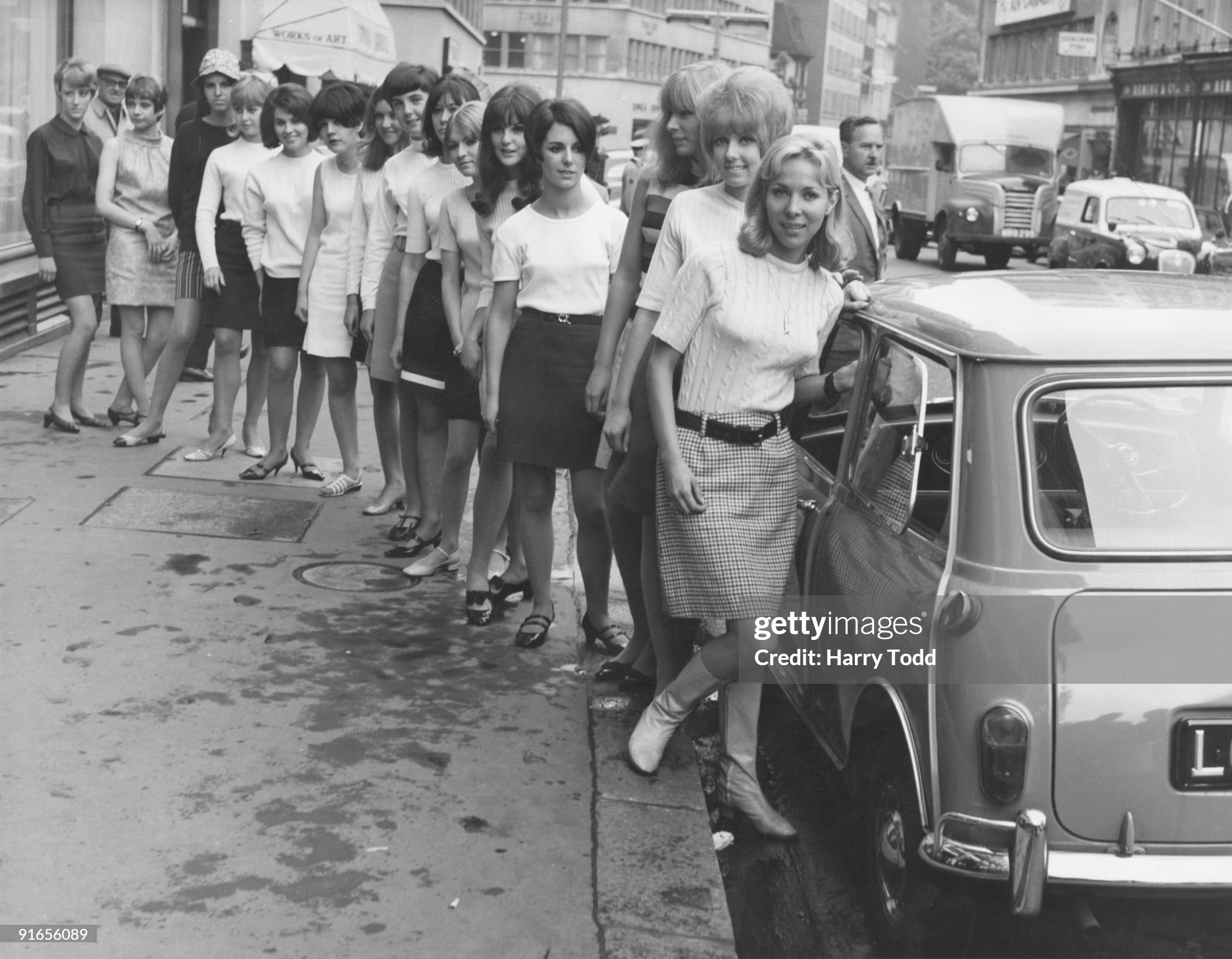 Fifteen young women in mini skirts wait to board a BMC Mini outside University Motors in Conduit street, London, 21st July 1966.