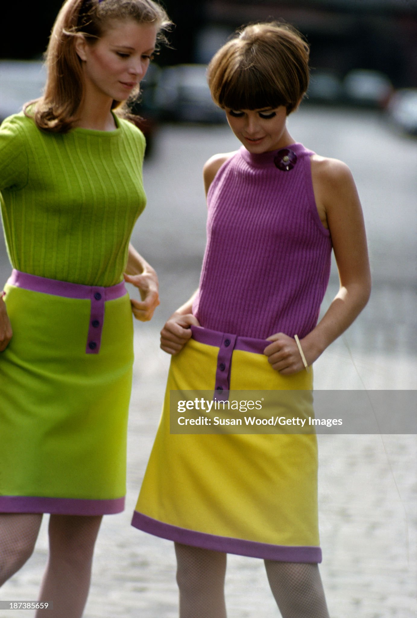 Two unidentified models, one in a green sweater and green skirt and the other in a purple sleeveless top and yellow skirt, pose together in New York in September 1966. 