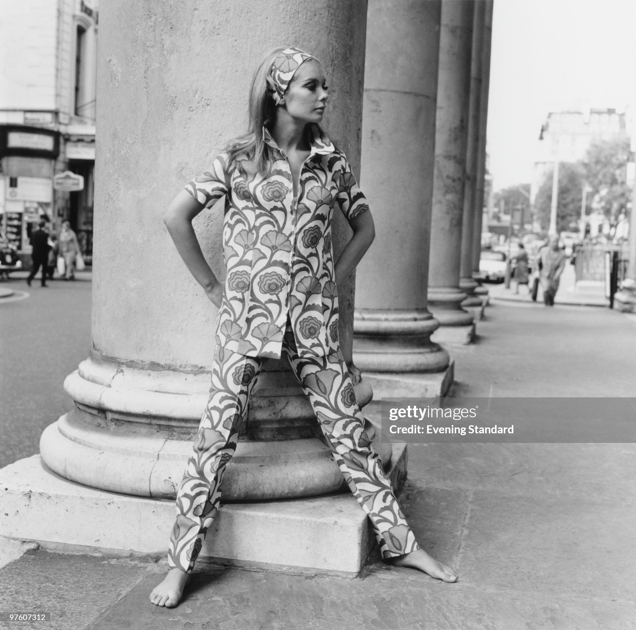 A woman modeling a floral-pattern trouser suit with matching headband in 1967.