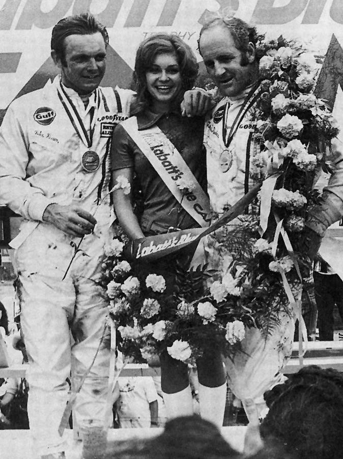 Peter Revson and Denny Hulme with a beauty queen in 1969.