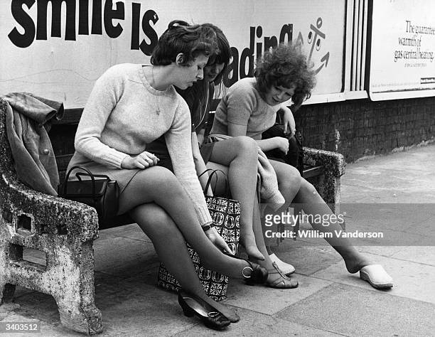 Footsore office girls rest their weary feet in Bow, East London, on 3rd July 1969 as they make their way to work during a one-day strike by underground signalmen. 