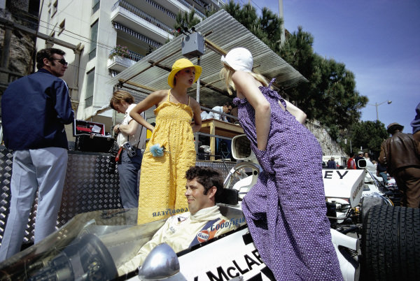 Brian Redman, McLaren M19A Ford, sits in his car as two models pose for a photoshoot on May 14, 1972 at the Monaco Grand Prix. 