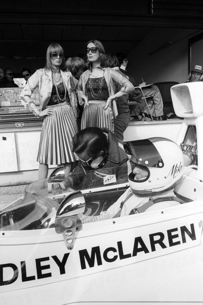 Ninth placed Mike Hailwood in the pits during practice with two women posing in the background at the Spanish Grand Prix in Jarama, Spain, on 28 April 1974. 