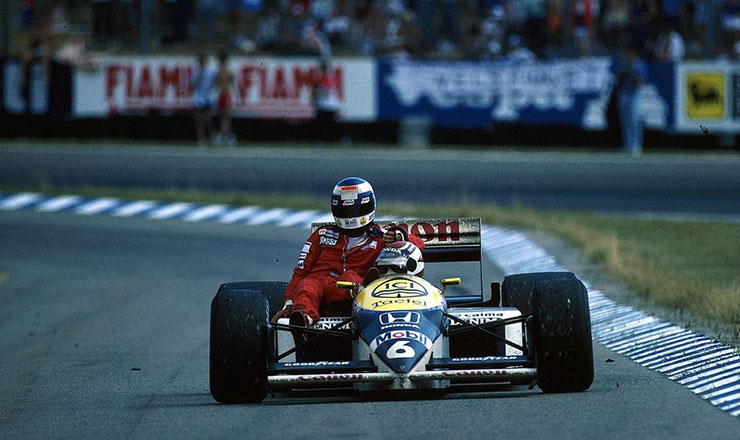 Keke Rosberg hitching a ride on Nelson Piquet's car after running out of fuel at the German Grand Prix at the Hockenheimring on 27 July 1986.