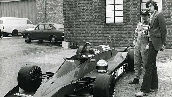 Gordon Murray and Niki Lauda stand beside BT48 racing car at Brabham factory.