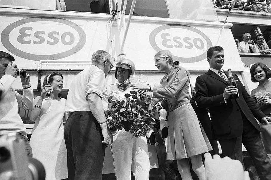 Jack Brabham enjoys his achievement and a glass of champagne on the podium after winning the French GP at Le Mans in 1967. 