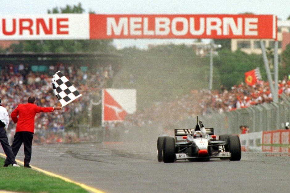 Sir Jack Brabham waves the chequered flag as David Coulthard in a McLaren crosses the finish line to win the Australian Grand Prix in Melbourne in March, 1997.