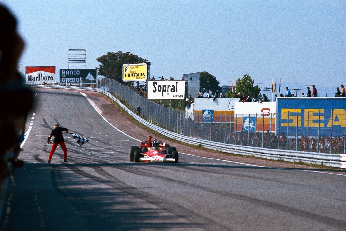 McLaren driver James Hunt, closely followed by the overlapped Ferrari of Regazzoni, crosses the line and takes the chequered flag to win the Jarama Grand Prix near Madrid, Spain, on 02 May 1976.