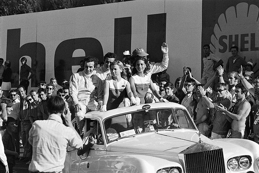 Race winner Jackie Stewart (covered, right hand), second placed Jean-Pierre Beltoise (left hand) and third Jacky Ickx enjoy their victory surrounded by cheering crowds after the 1969 French GP.