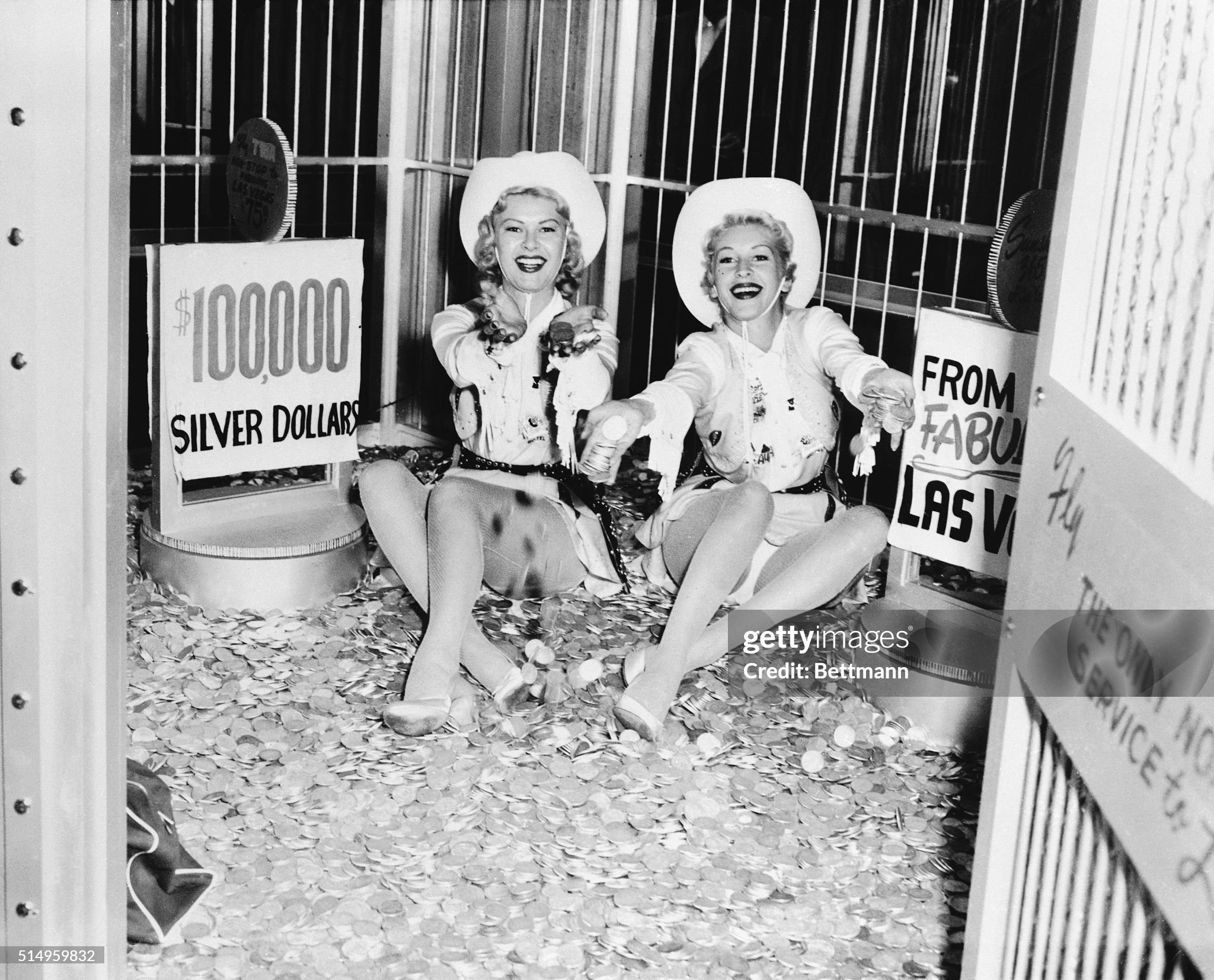 In a Chicago airlines ticket office, cowgirls Jane Pike (left) and Karolee Kelly sit on a pile of 100,000 silver dollars, 5,900 pounds in weight, on 20 October 1954 to advertise the two main tourist attractions of Las Vegas: legalized gambling and women. For the next four days the girls would just sit in the TWA office and jingle the coins.