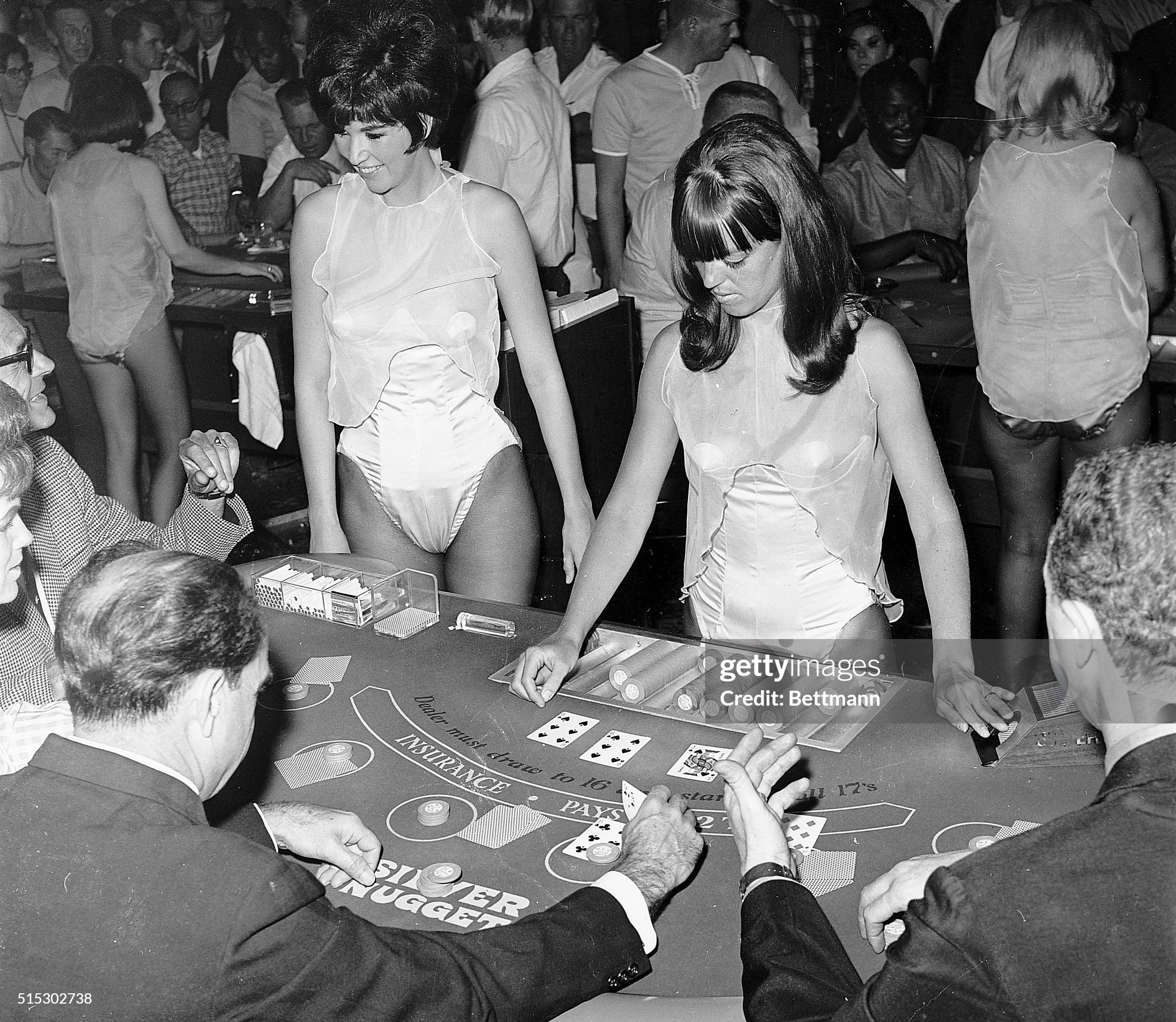 Black Jack dealers Dianne McMillin (left) and Jaye Boack work in the pit at the Silver Nugget Casino in Las Vegas on 16 April 1966, wearing costumes with see-through tops. The management brought the girls on the 1 to 8 AM shift, contending they were not topless (they had on chiffon transparent tops with pasties underneath) and, therefore, should not cause objections from the gaming commission or the Attorney General, who earlier said he would go to court to get an injunction against them. The women are shown dealing to a table of players. 