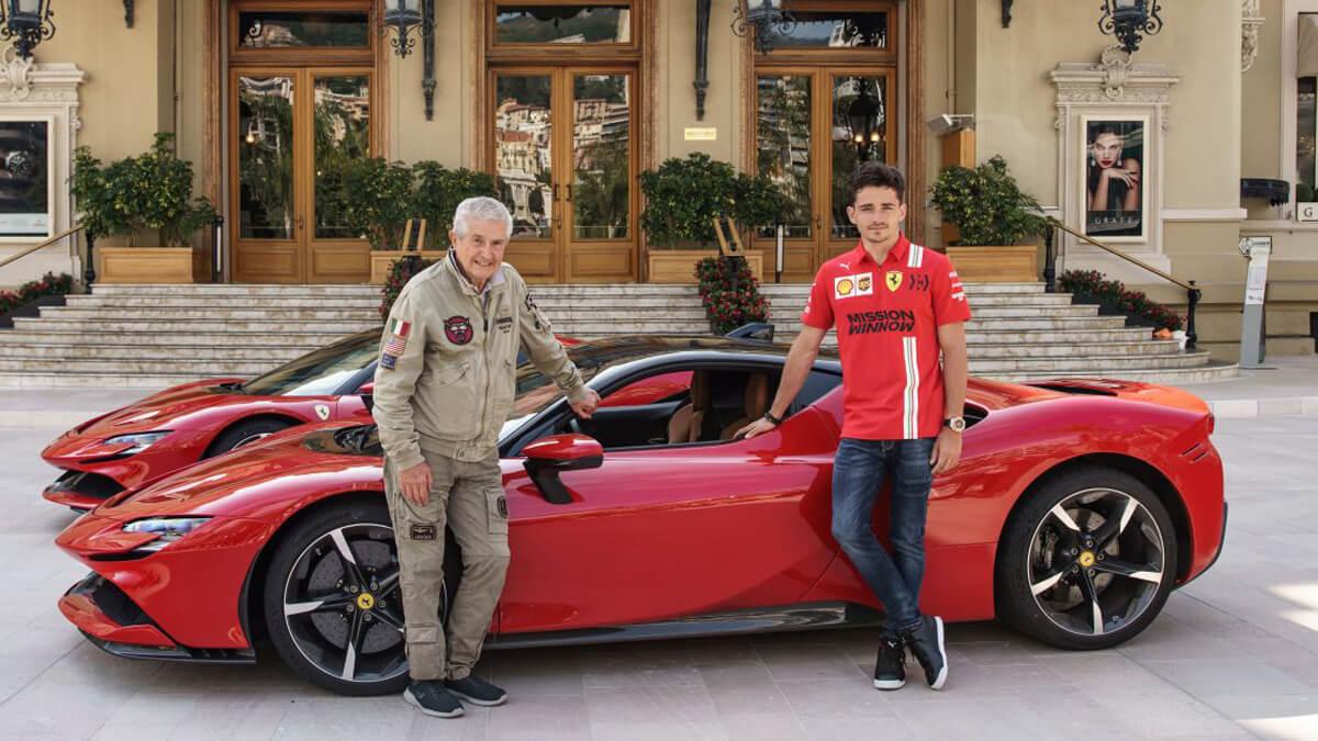Charles Leclerc with Claude Lelouch in front of two Ferraris.