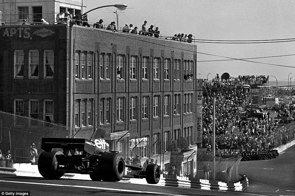 One of the trickier corners on the circuit was the first one as following the start straight a right turn would immediately throw the car into a short but sharp decline down Linden Avenue, as demonstrated here by Jody Scheckter, whose unbalanced Tyrrell has its right front off the ground. Spectators on the left enjoy the view from a building that has since been demolished.