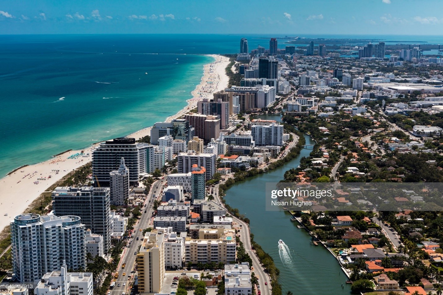 Aerial view of South Beach Miami, Florida. Cityscape with buildings along the beach on a beautiful sunny day, people on beach and ocean, Collins Avenue and boat on Indian Creek. 