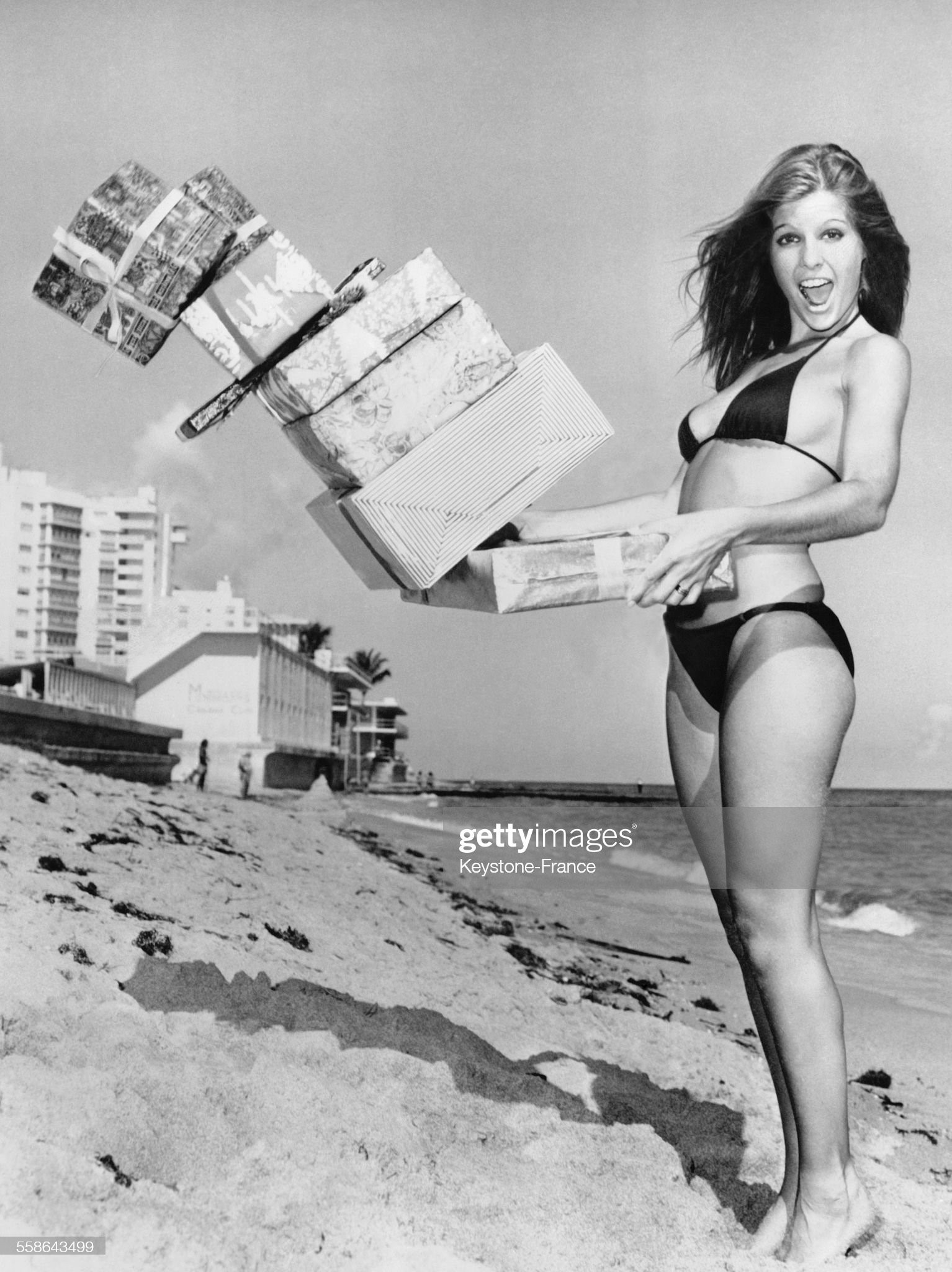 Young girl on a beach with gifts to announce the start of Christmas shopping in Miami, Florida. 