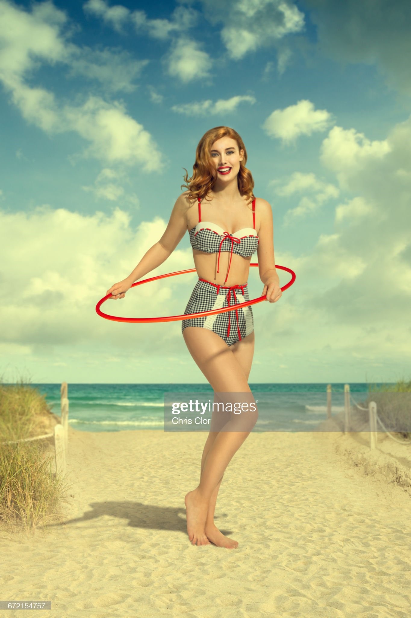 Caucasian woman wearing bikini holding plastic hoop at beach.