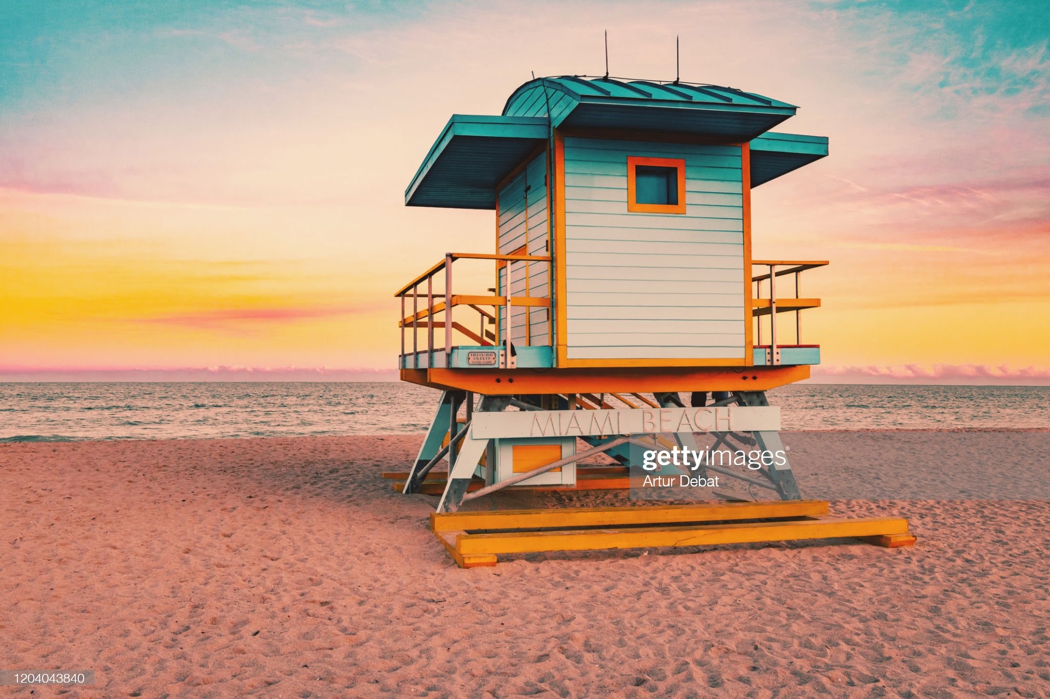 Colorful Miami Beach lifeguard tower with stunning sunset sky and empty beach.
