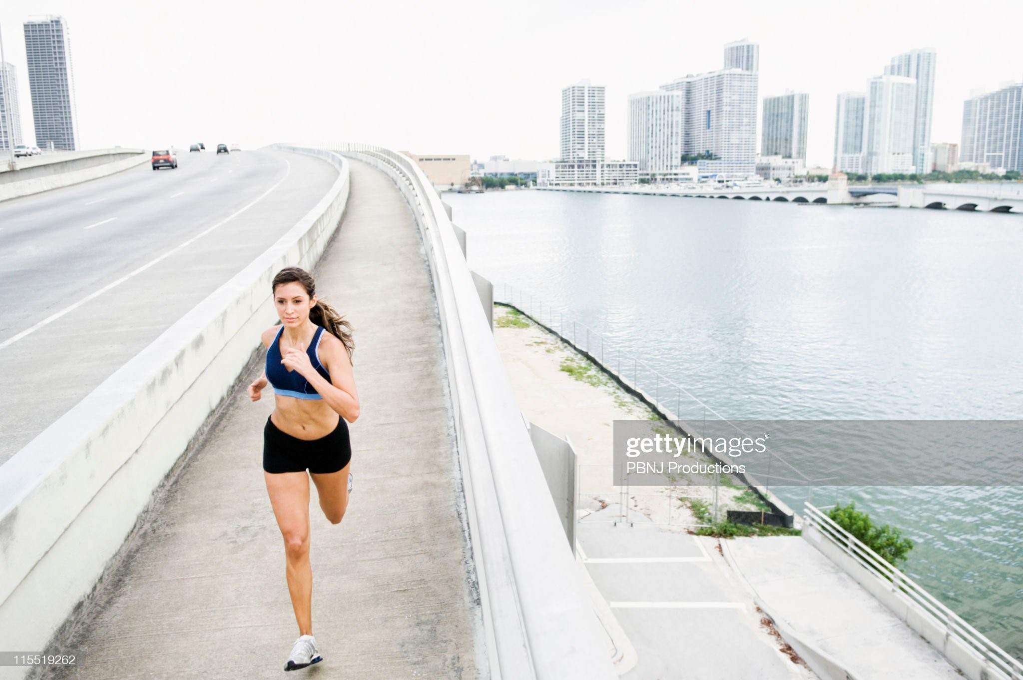 Hispanic woman running near urban waterfront. 