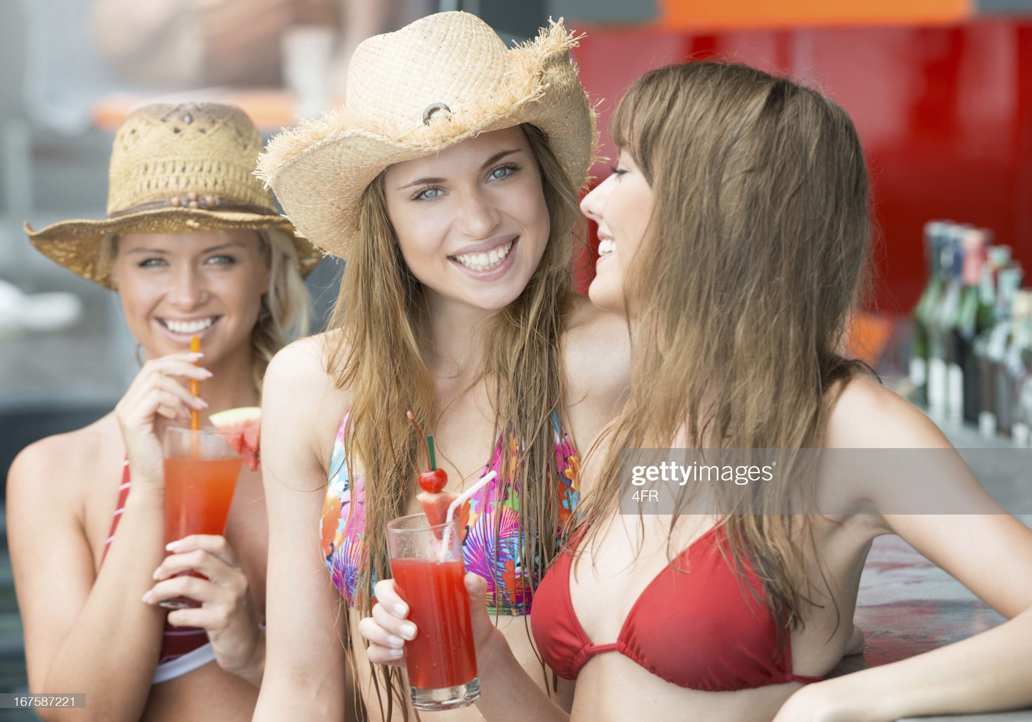 Three beautiful women drinking cocktails at the pool bar on vacation. 