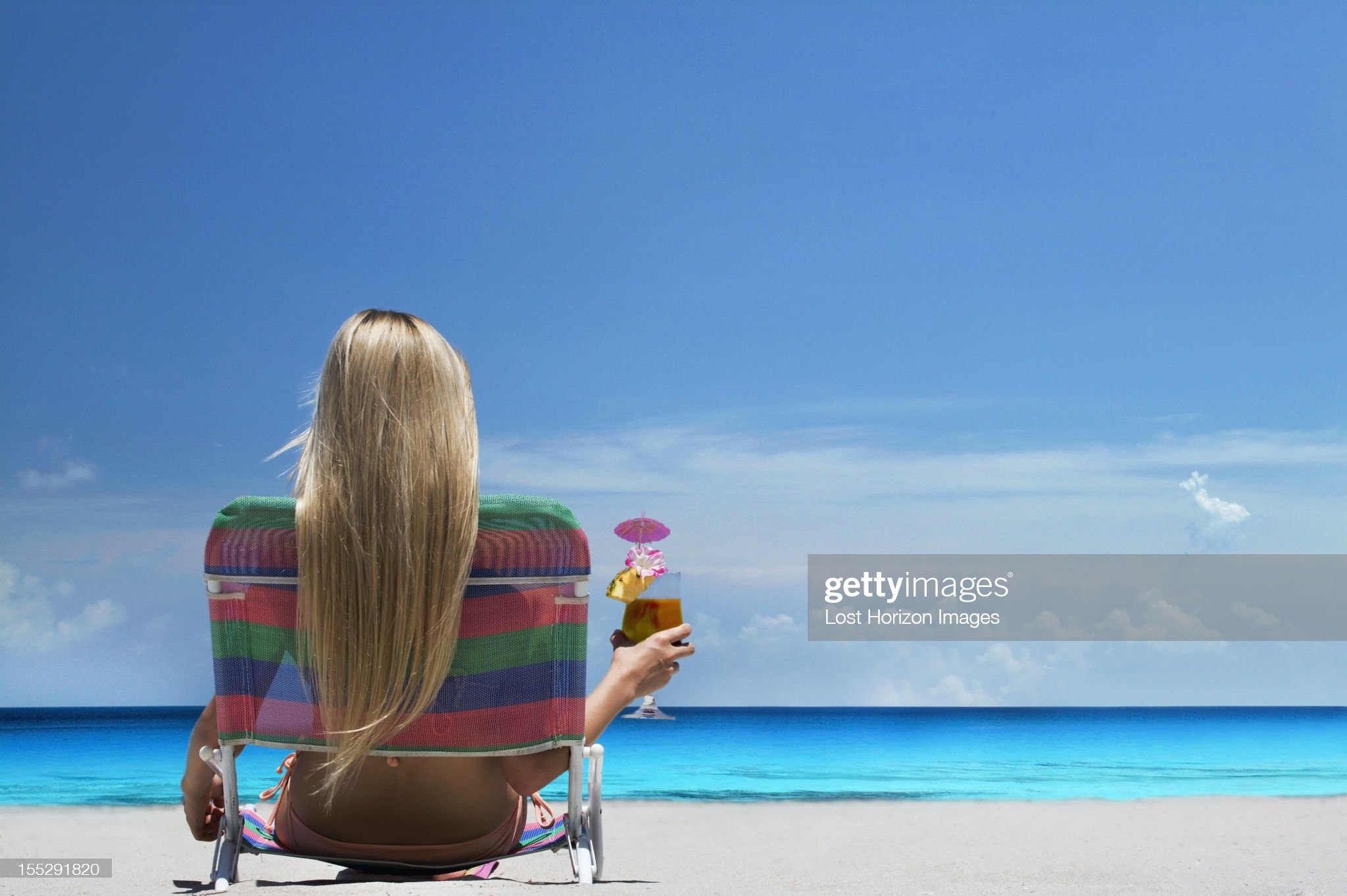 Woman relaxing in lawn chair on beach. 