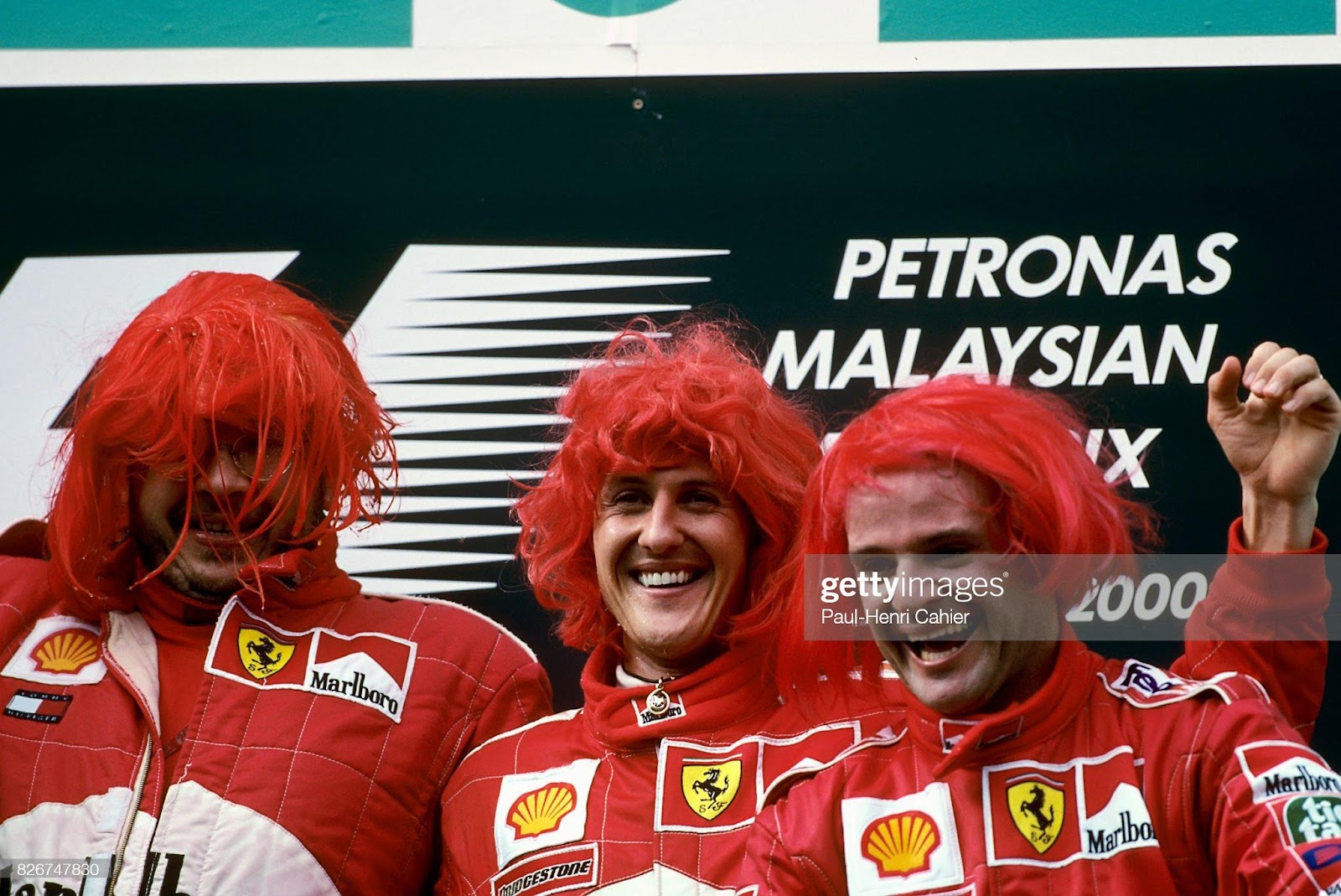 Ross Brawn, Michael Schumacher and Rubens Barrichello wearing red wigs on the podium of the Grand Prix of Malaysia at Sepang International Circuit on 22 October 2000.