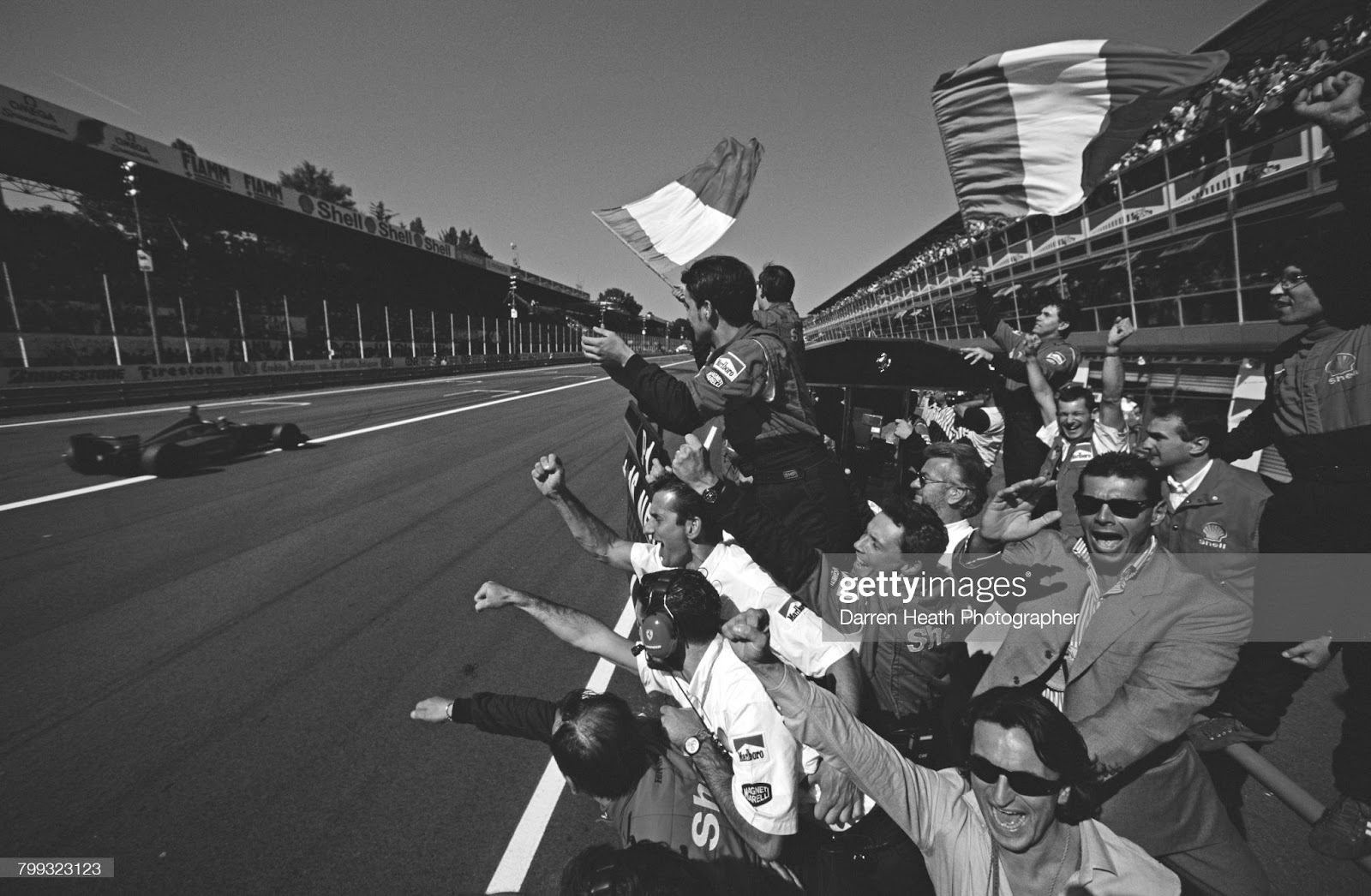 Scuderia Ferrari team members salute Michael Schumacher from the pit lane wall as he takes the chequered flag driving the n.1 Ferrari F310 V10 to win the F1 Italian Grand Prix on 8 September 1996 at the Autodromo Nazionale Monza. 