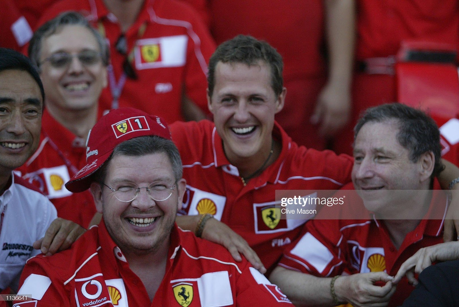 Ross Brawn (left) tries on the new World Champion Michael Schumacher's (center) cap while Jean Todt (right) looks on during a team photo to celebrate the German’s title at the F1 French Grand Prix at Nevers Magny-Cours Circuit, France, on July 21, 2002.