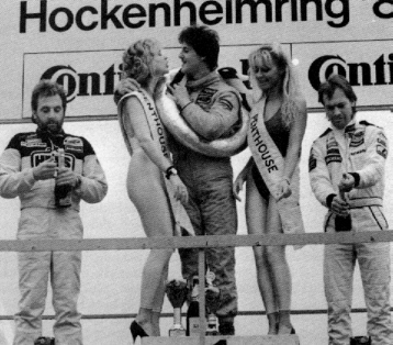 Michael Schumacher on the podium with two girls.