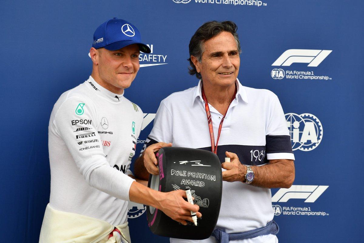 Finn Valtteri Bottas, on June 30, 2018, shortly after taking pole at the Austrian Grand Prix, taking the Pirelli trophy for his achievement from Nelson Piquet.