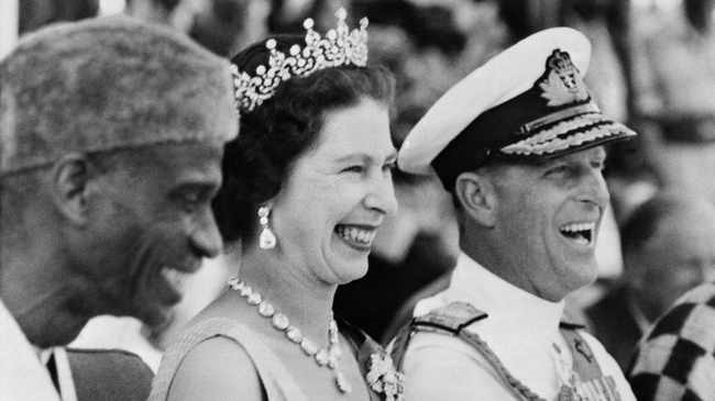 Britain's Queen Elizabeth II and Prince Philip, Duke of Edinburgh, laugh on December 4, 1961 as they watch the Susu dancers during their visit at the Northern Province of Sierra Leone. 