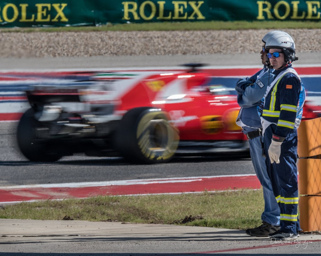 Race marshals at Circuit of the Americas are passed by Sebastian Vettel of Ferrari during the 2017 United States Grand Prix. 