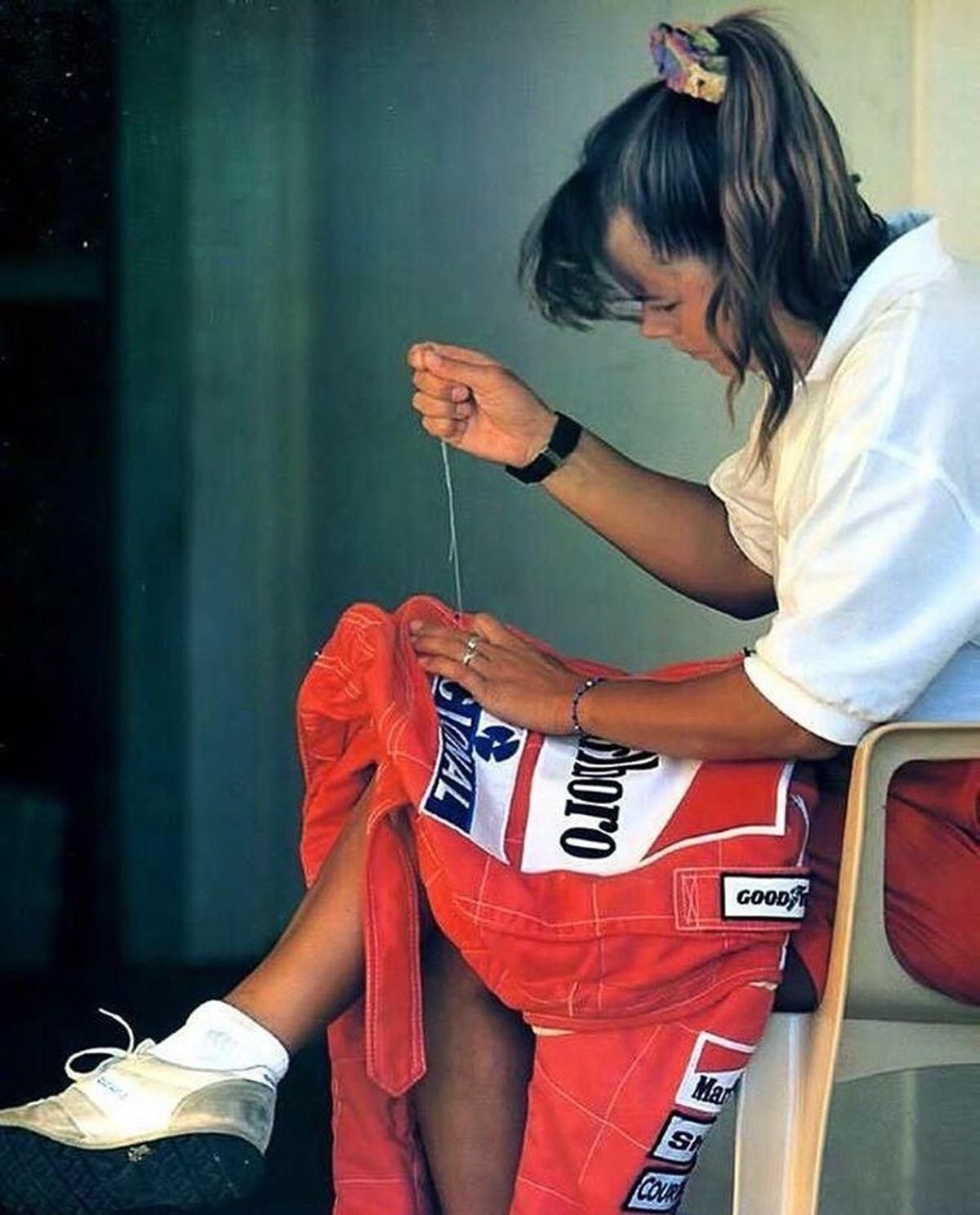 Ayrton Senna’s girlfriend makes last minute alterations to his racing overalls.