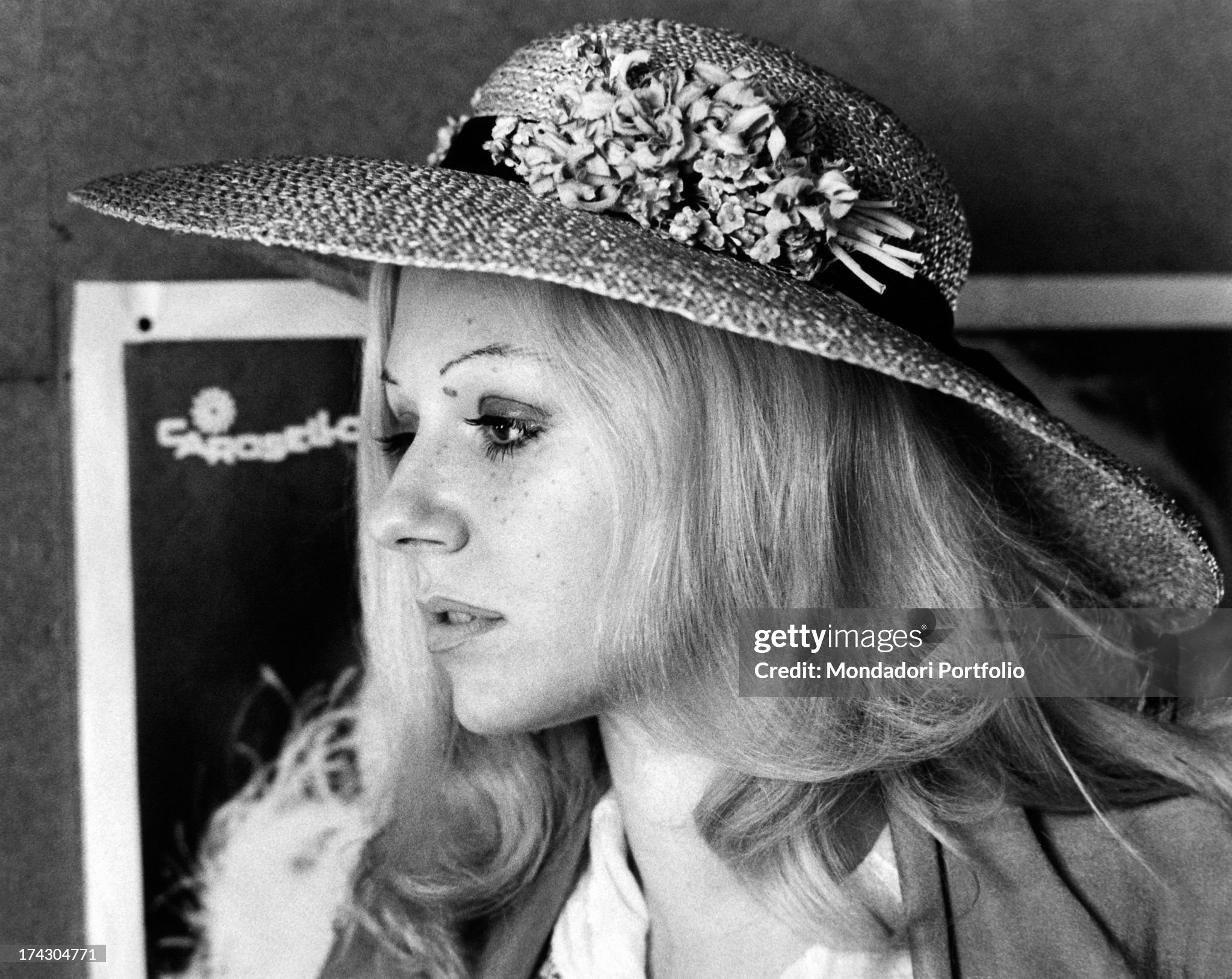 A profile picture of Ombretta Colli looking pensive in Milan, Italy, in 1972; behind her there is a poster with the word Carousel, the record company with which the singer published. 