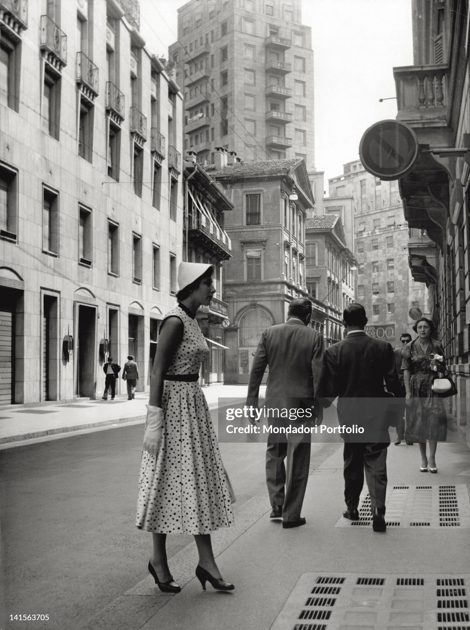 An elegantly dressed girl is looking at a window shop in via Monte Napoleone in Milan in the '50s. 