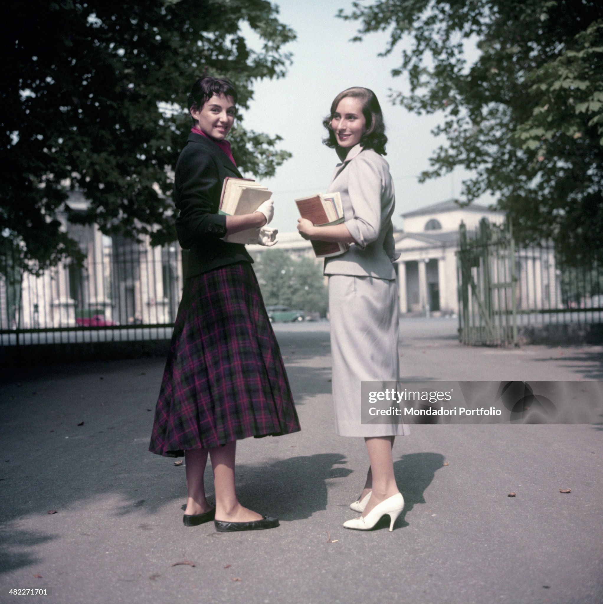 Two young Italian girls, Cristina Vanini and Paola Del Vicario, looking into the camera and smiling in Milan in 1955. 