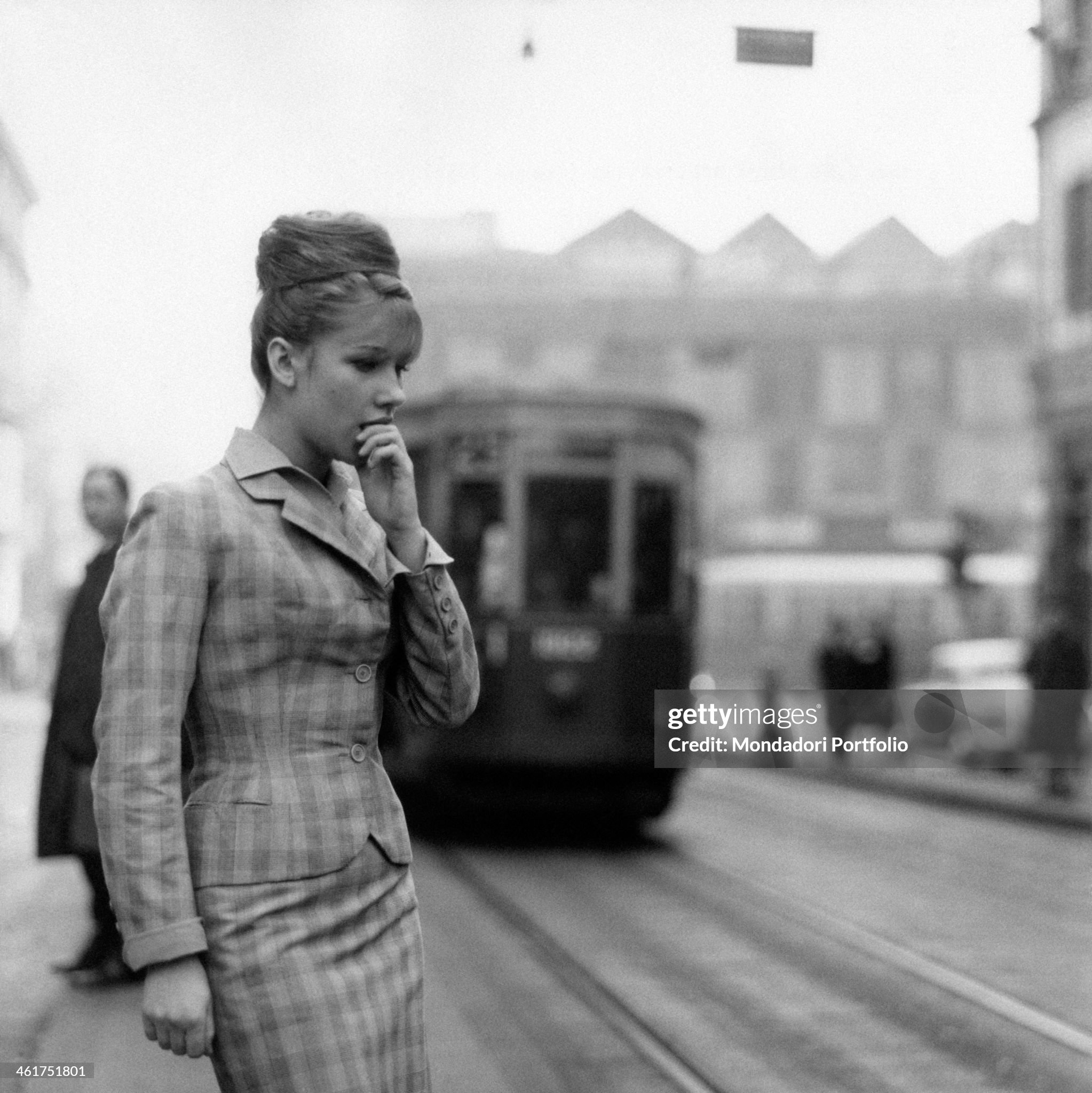 A young woman looking thoughtful by the tram rails in Milan in April 1961.